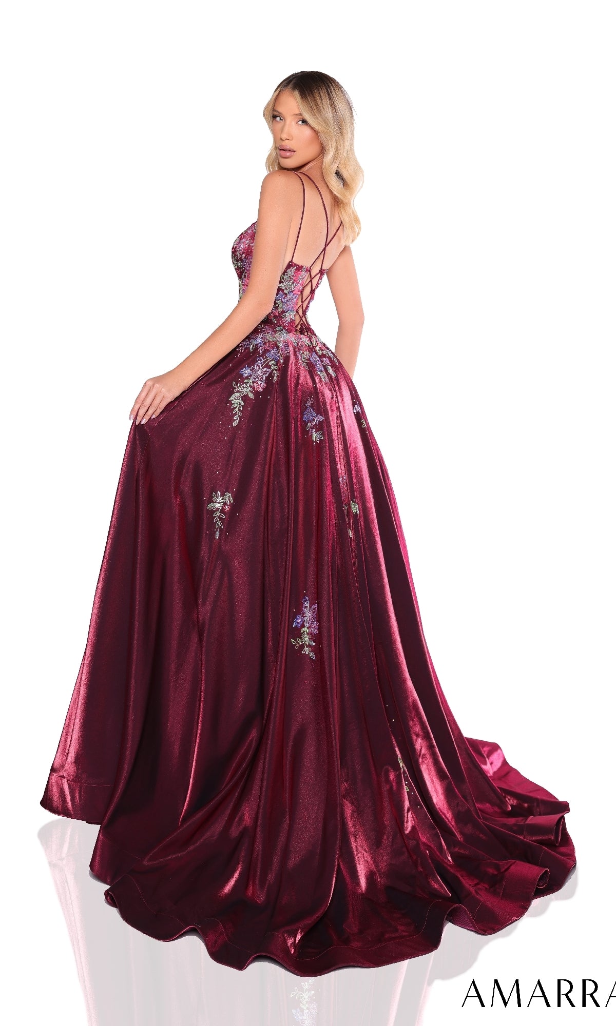A woman poses against a white background wearing the Amarra 88379 long prom dress in burgundy, featuring elegant floral embroidery and a strappy open back.